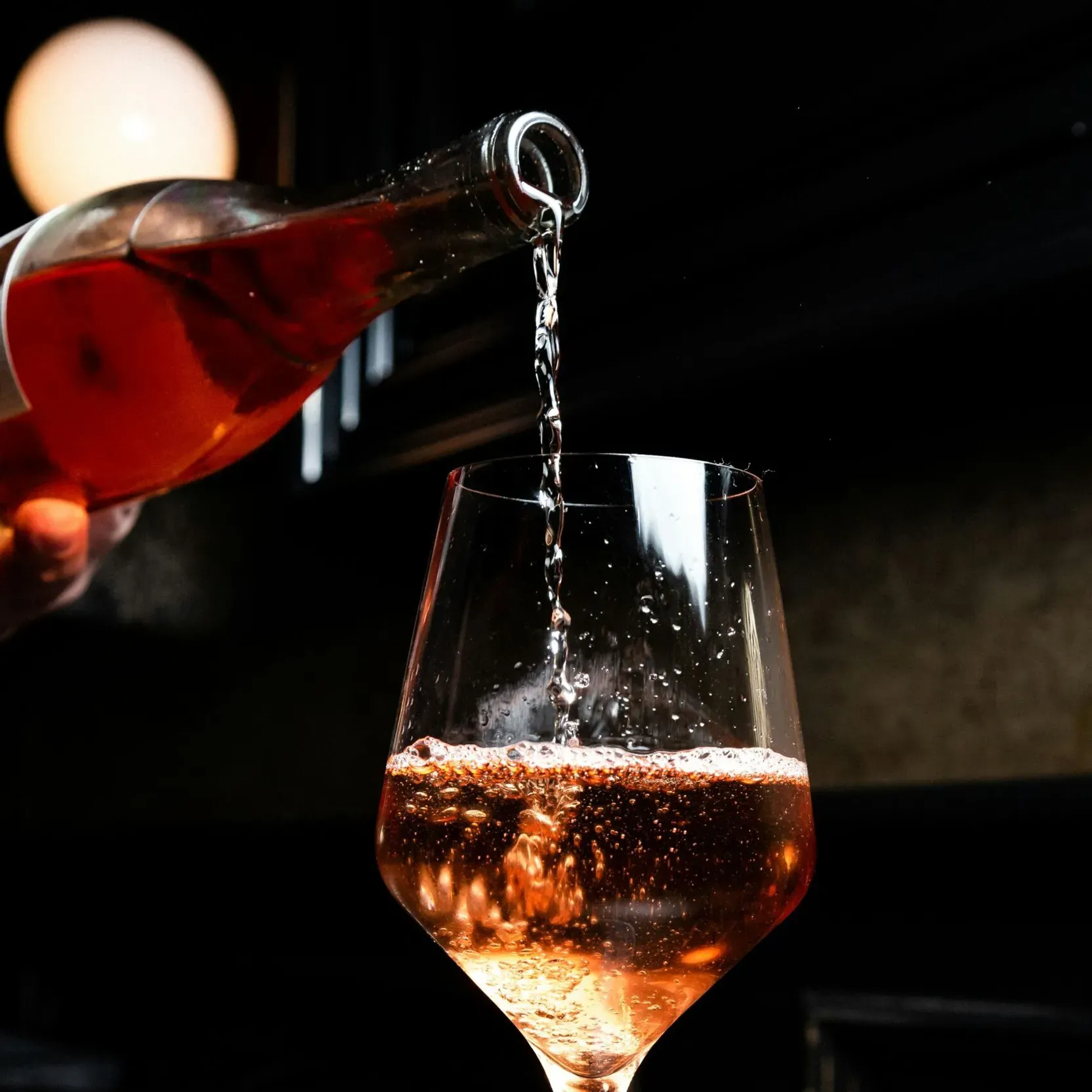Glass into which rosé wine is being poured.