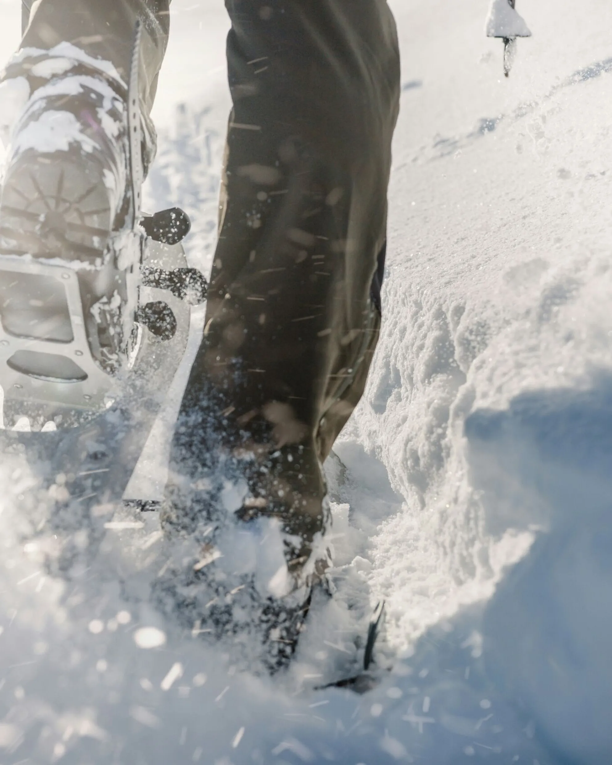 Close-up of snowshoes sinking into fresh snow during a winter hike, highlighting the texture of the snow and the motion of footsteps.