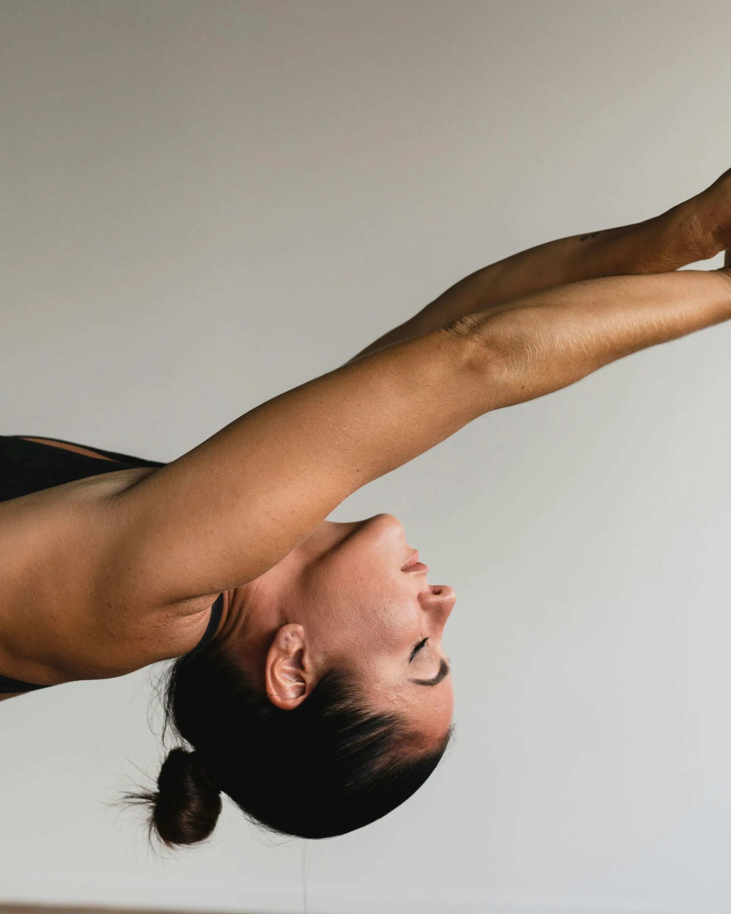 Woman in Urdhva Dhanurasana (Wheel Pose) yoga position, with her back arched backward and arms raised above her head, performing a backbend exercise.