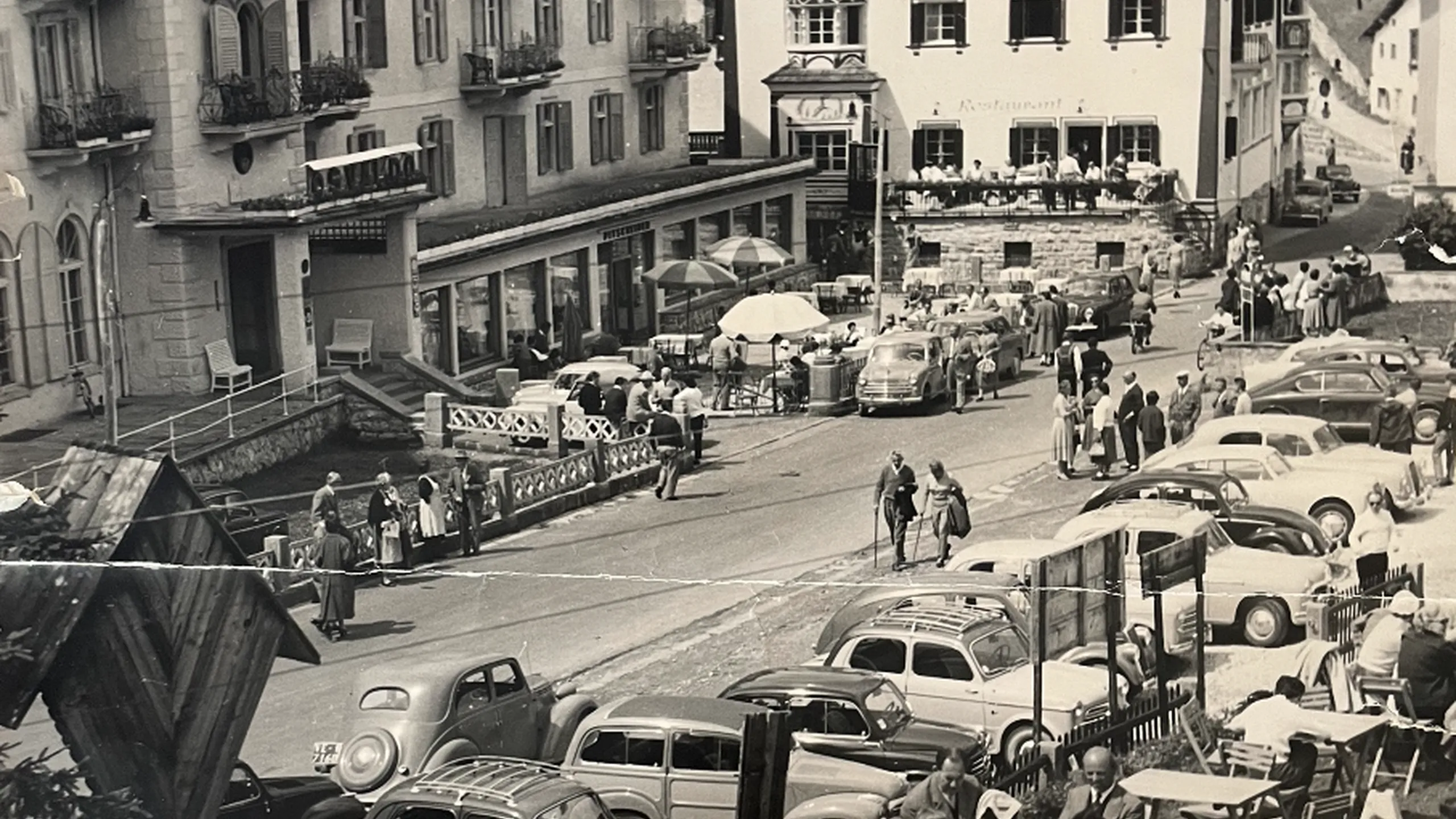 View of the terrace and square in front of Hotel Oswald, filled with people, highlighting how the hotel has always been a landmark for the local community.