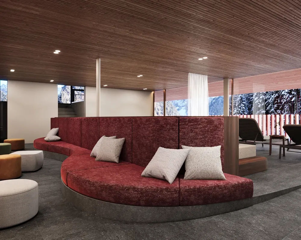 Relax lounge in the Spa area featuring red velvet sofas with cushions, round poufs, and sun loungers, softly lit, with a view of the forest surrounding the hotel for complete relaxation.