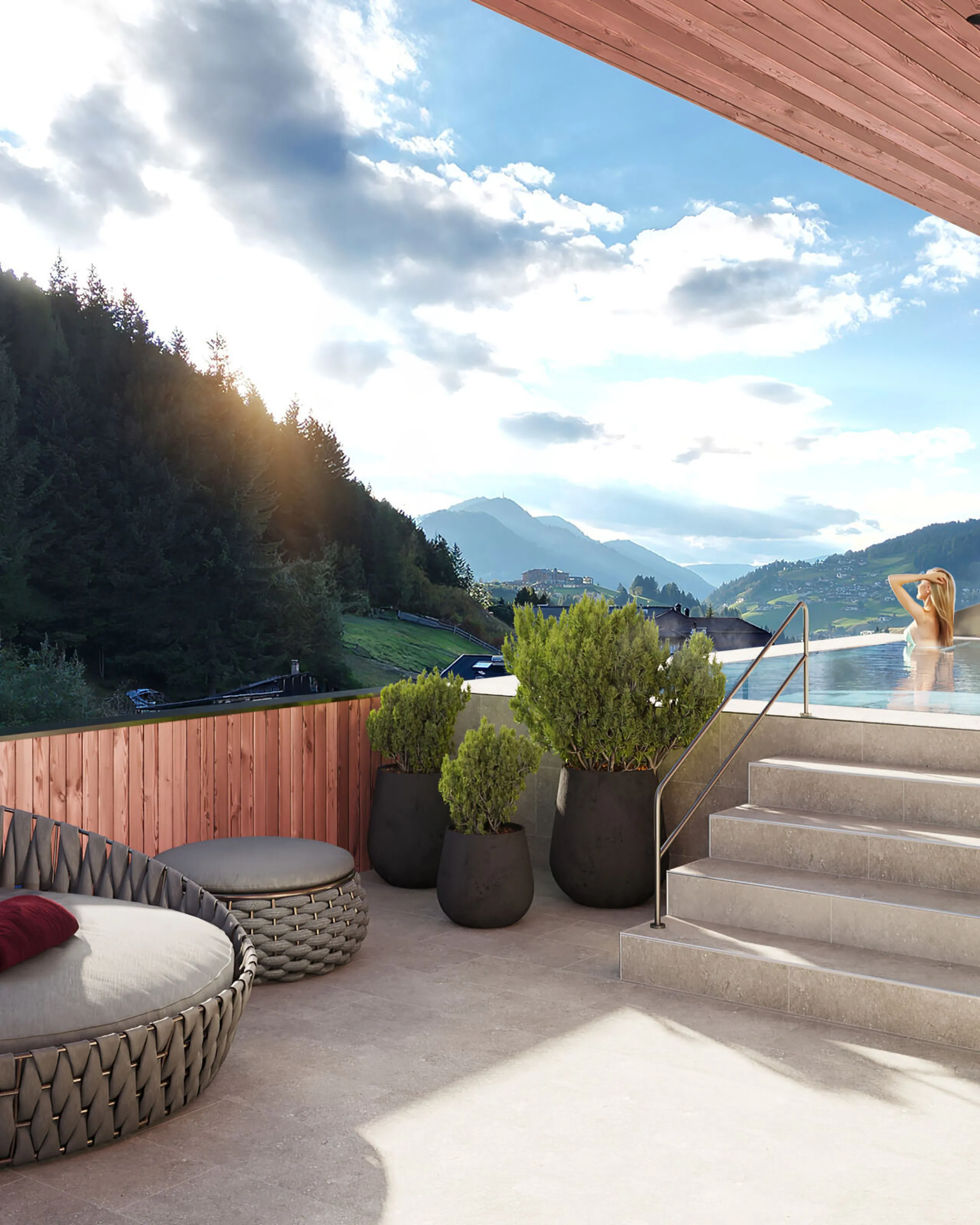 Rooftop whirlpool at Hotel Oswald in Selva di Val Gardena, surrounded by the majestic Dolomites on a bright sunny day, with a cozy round sofa nearby for outdoor relaxation.