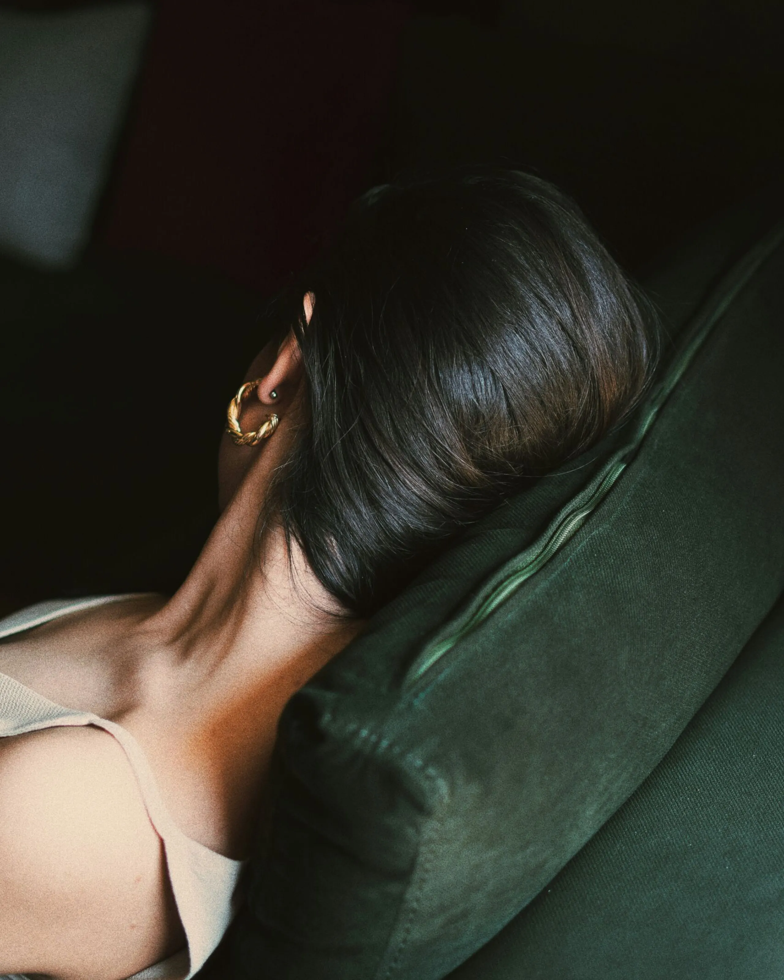 Woman relaxing on a dark green velvet armchair.