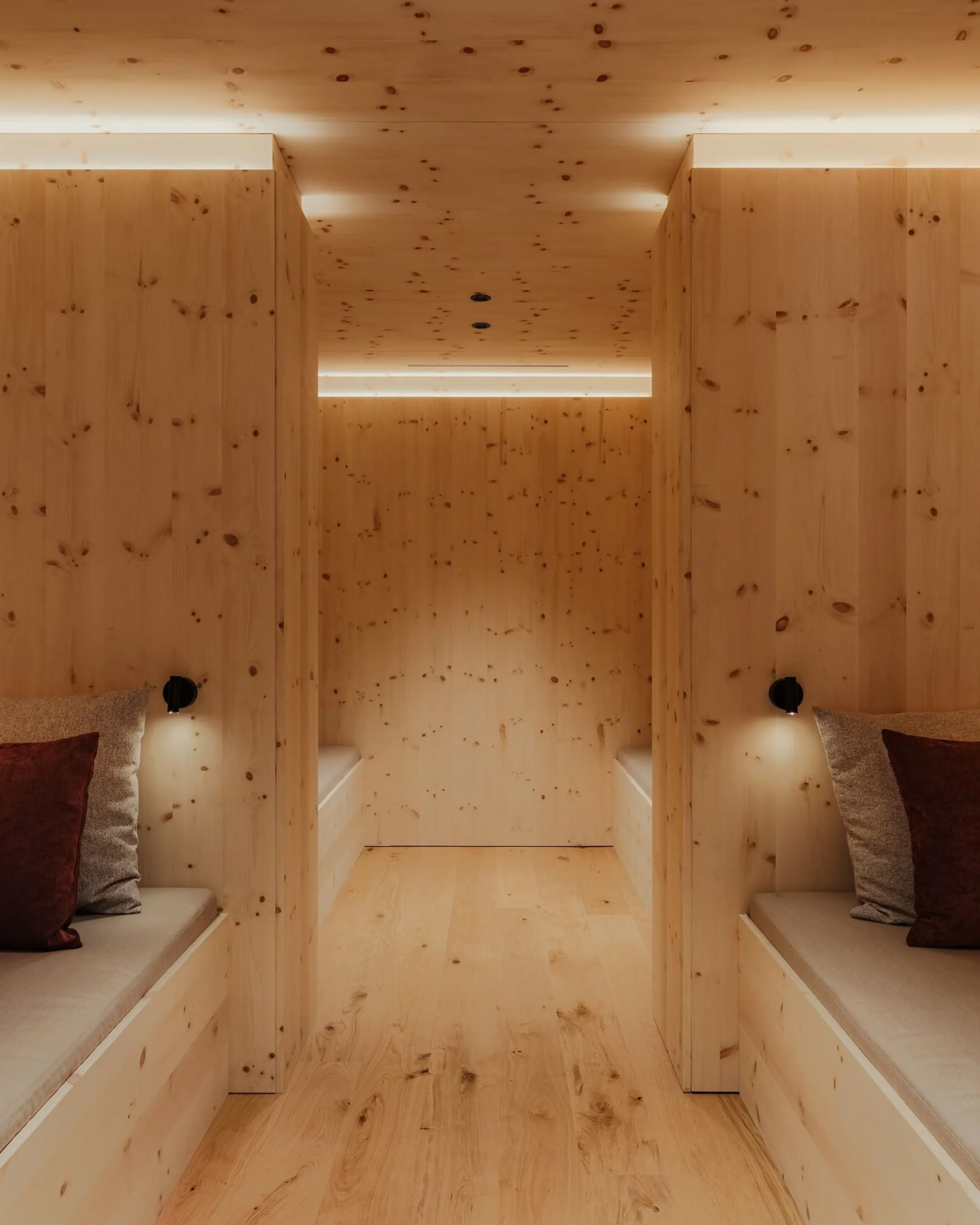 Peaceful Swiss pine relaxation room at The Oswald Grand Hotel, featuring light Swiss pine wood throughout the interior. Upholstered relaxation benches with soft cushions line both sides of the room, while indirect warm lighting enhances the tranquil atmosphere. The natural Swiss pine wood gives the space a warm alpine character.