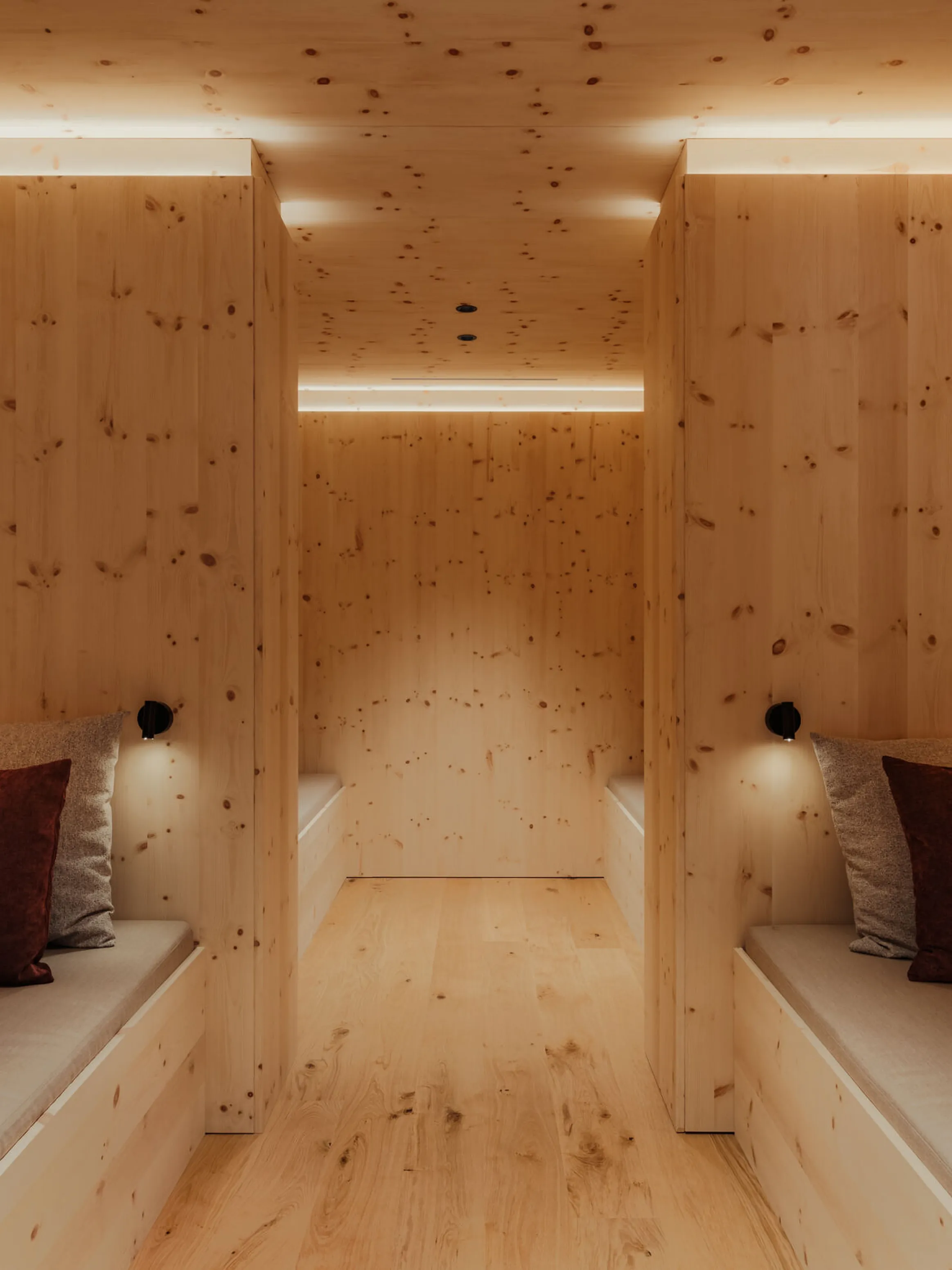 Cozy wooden room with two beige lounge seats, each adorned with burgundy and gray cushions. Soft ambient lighting creates a warm, serene atmosphere.